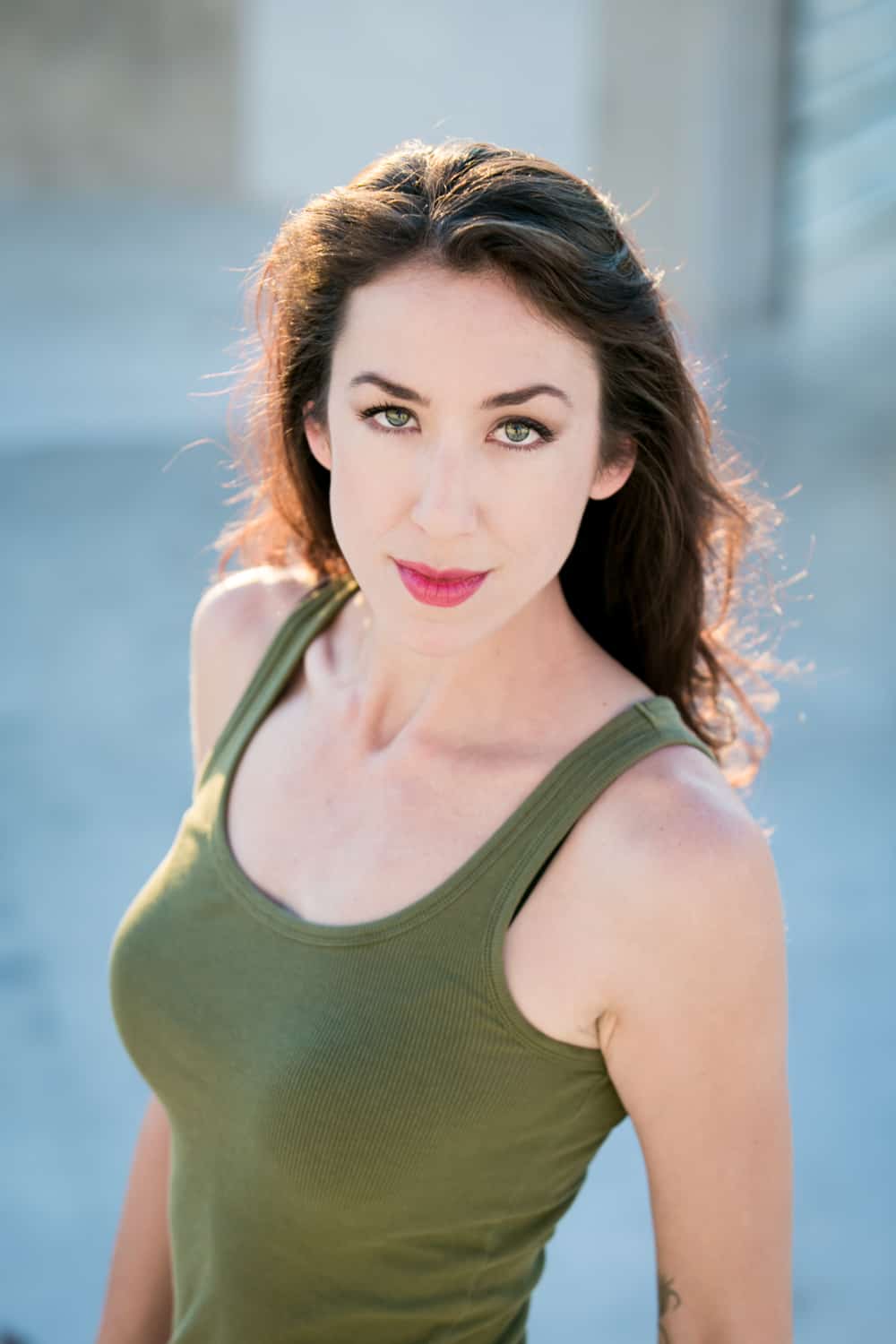 Headshot of model with long dark hair and olive tank top
