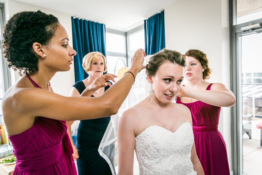 Bridesmaids adjusting veil of bride 
