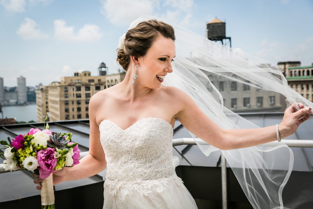 Portrait of bride touching blowing veil on rooftop for an article on how to get the wedding photos you want
