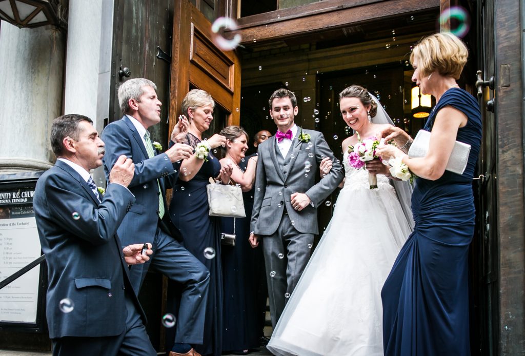 Bride and groom leaving church with guests blowing bubbles