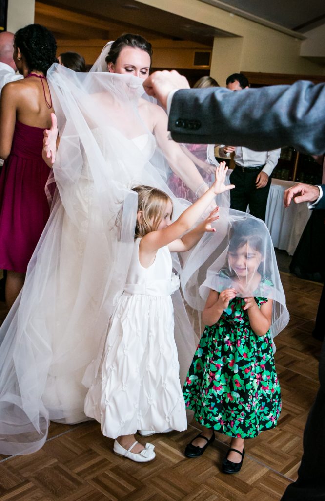 Little girls playing in bride's veil for an article on how to get the wedding photos you want