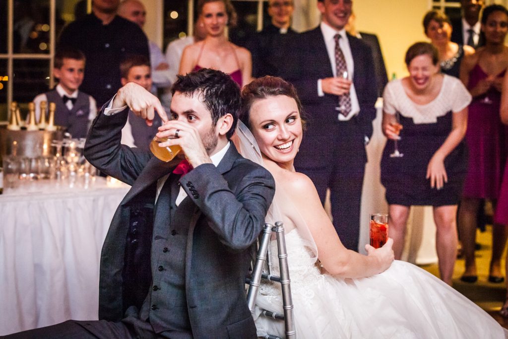 Bride and groom playing drinking game at wedding reception