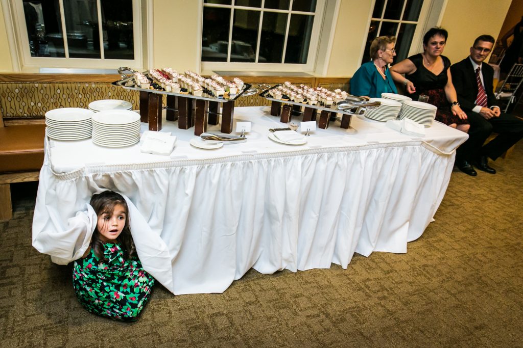 Little girl hiding under table at wedding reception