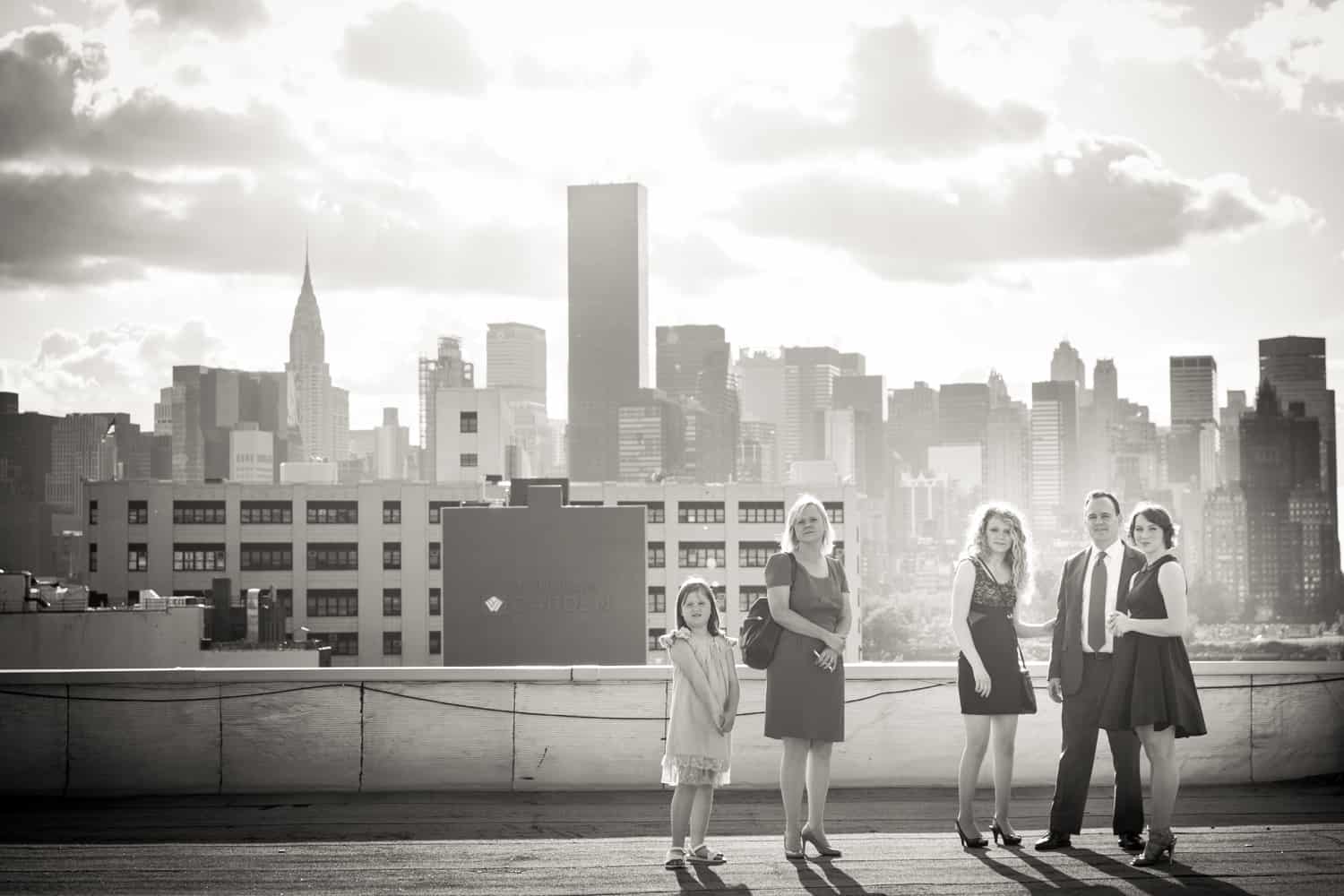 Black and white photo of family on roof with view of NYC skyline