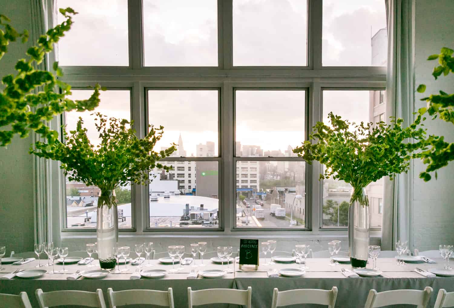 Table setting with tall vases and view of NYC skyline for an article on how to plan the perfect bar mitzvah