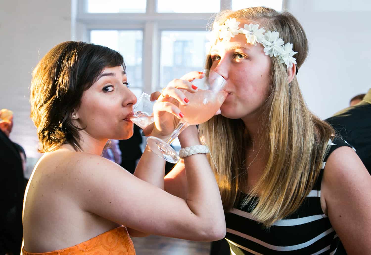 Two girls with entwined arms drinking from glasses for an article on how to plan the perfect bar mitzvah