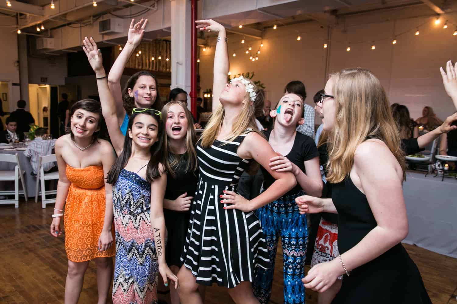 Girls dancing with arms above for an article on how to plan the perfect bar mitzvah