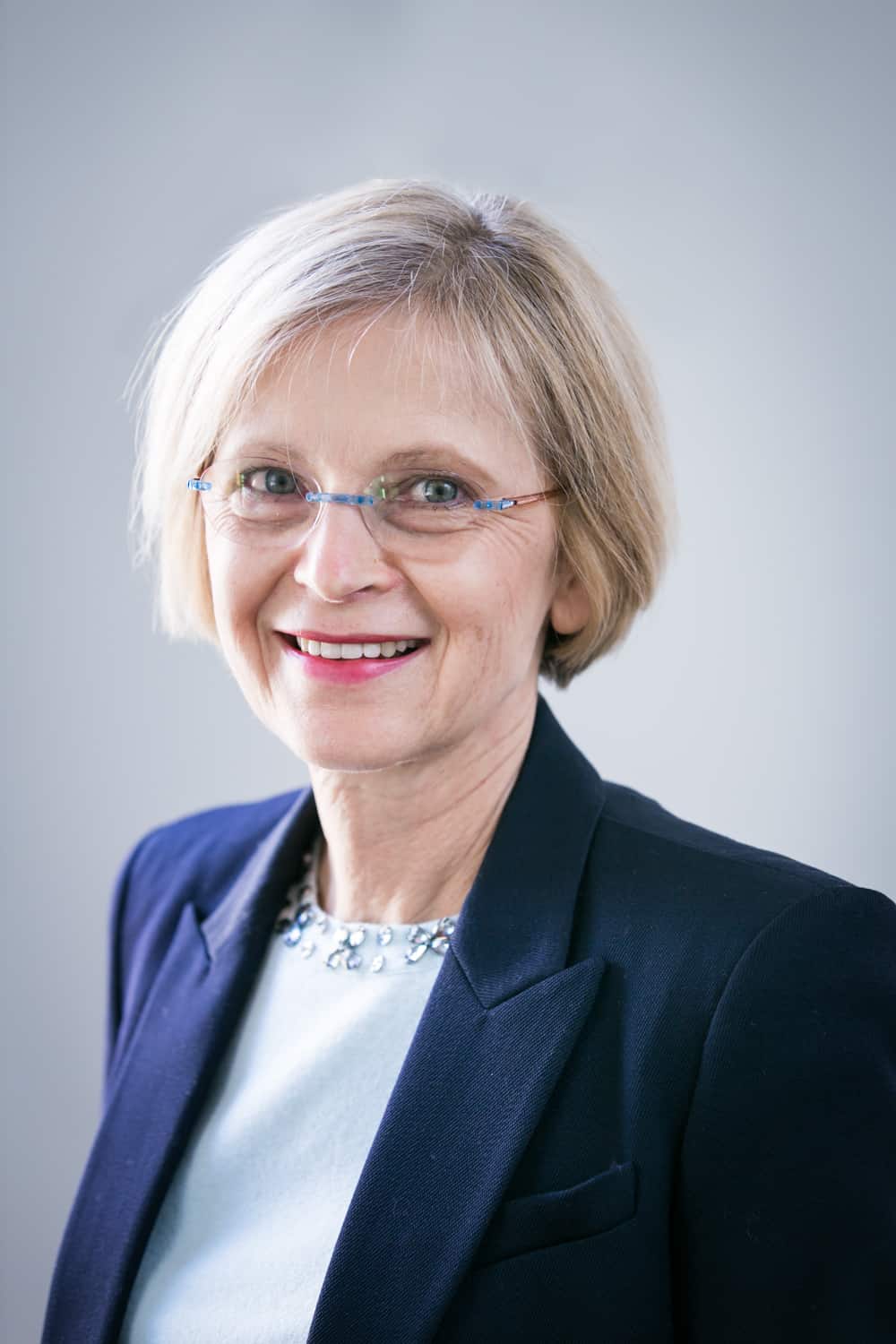 Older woman wearing navy blazer and glasses