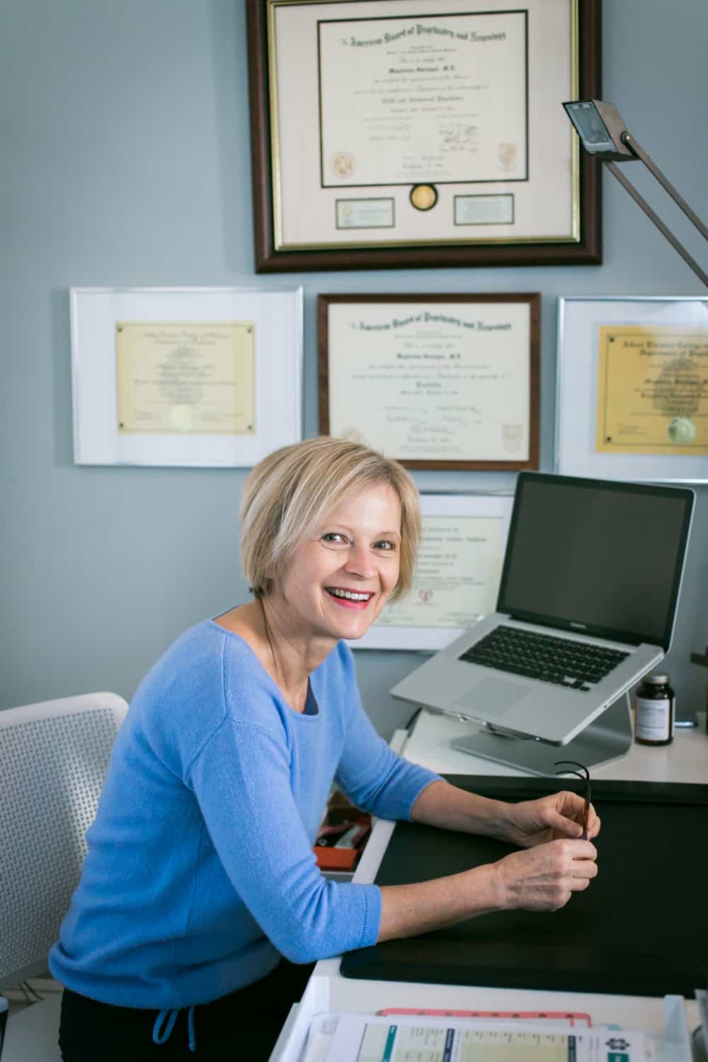 Professional portraits of a psychiatrist smiling at her desk