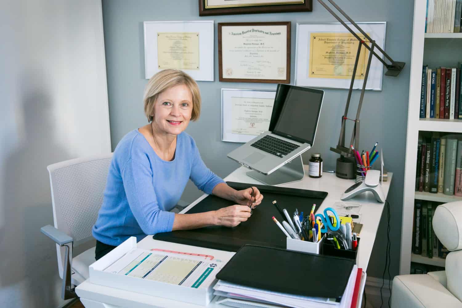 Professional portraits of a psychiatrist smiling at her desk