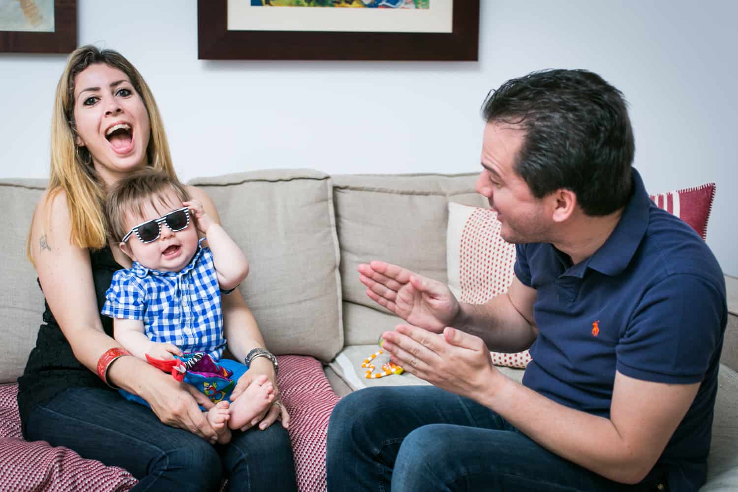 Father entertaining mother and baby wearing sunglasses