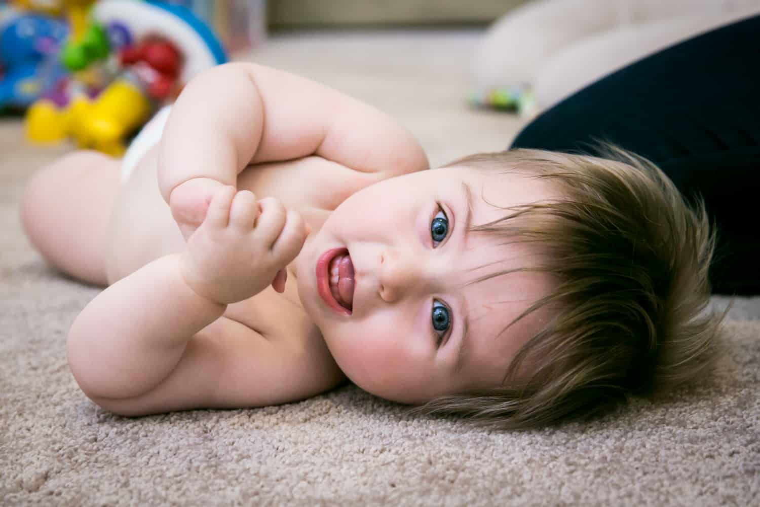 Baby boy wearing diaper rolling on carpet