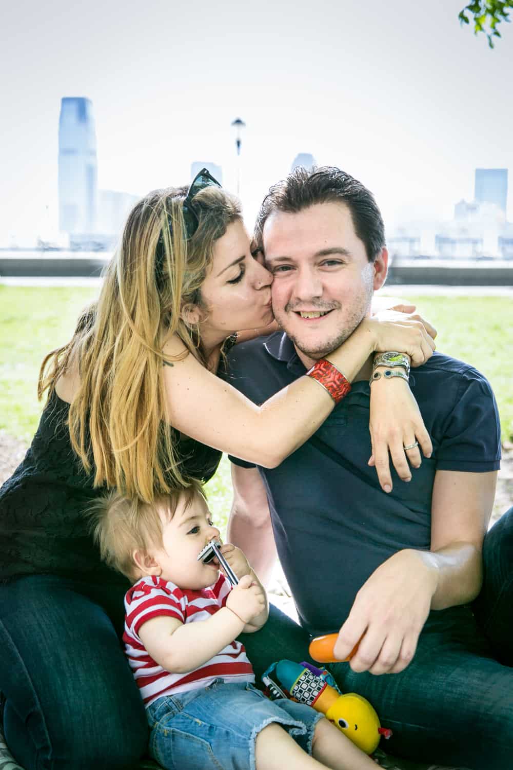 Mother kissing father on cheek during a Battery Park family portrait