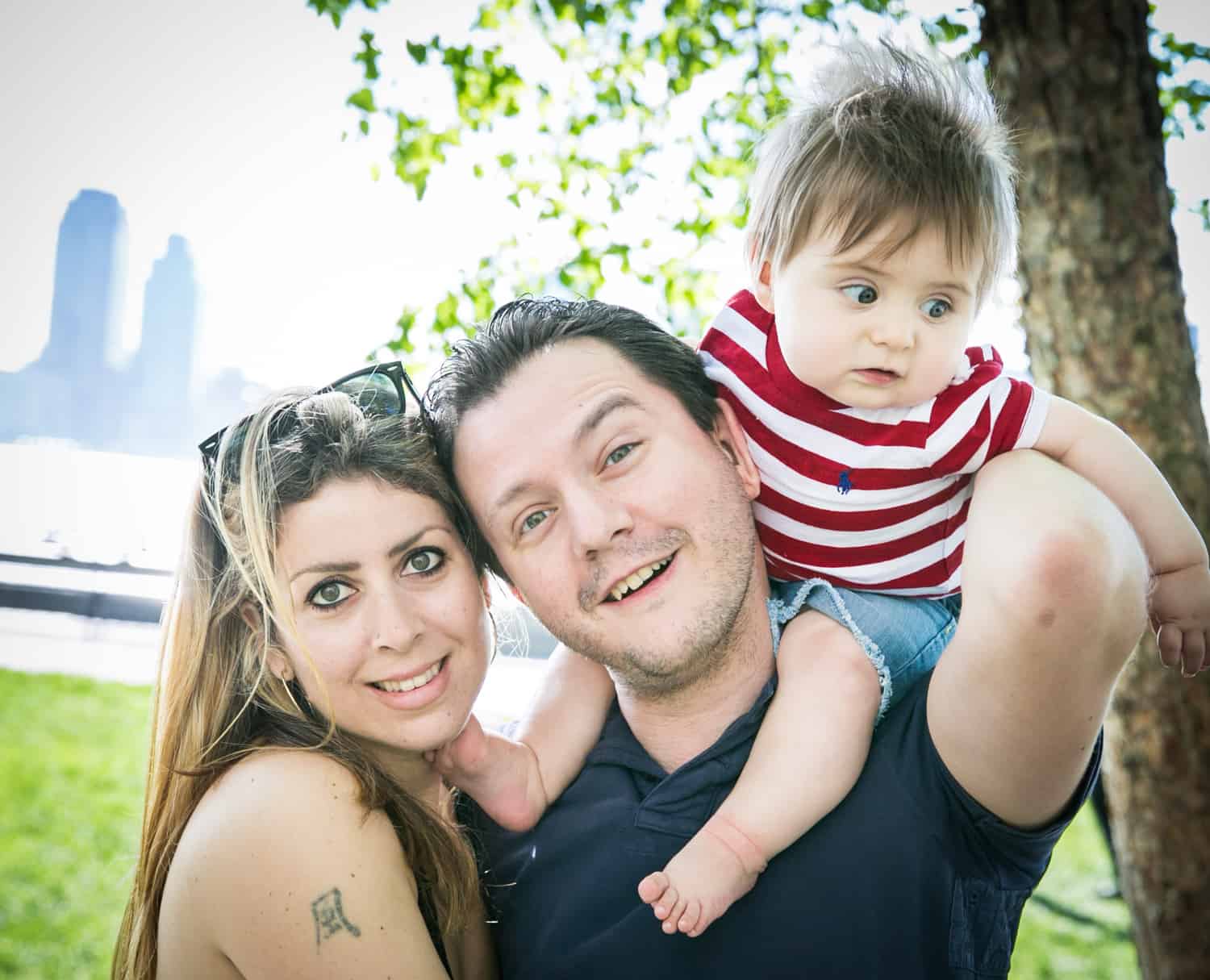 Parents and baby on father's shoulder during a Battery Park family portrait