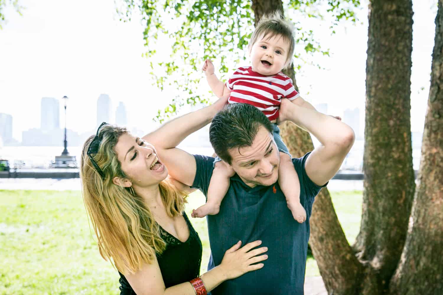 Parents playing with baby on father's shoulder during a Battery Park family portrait