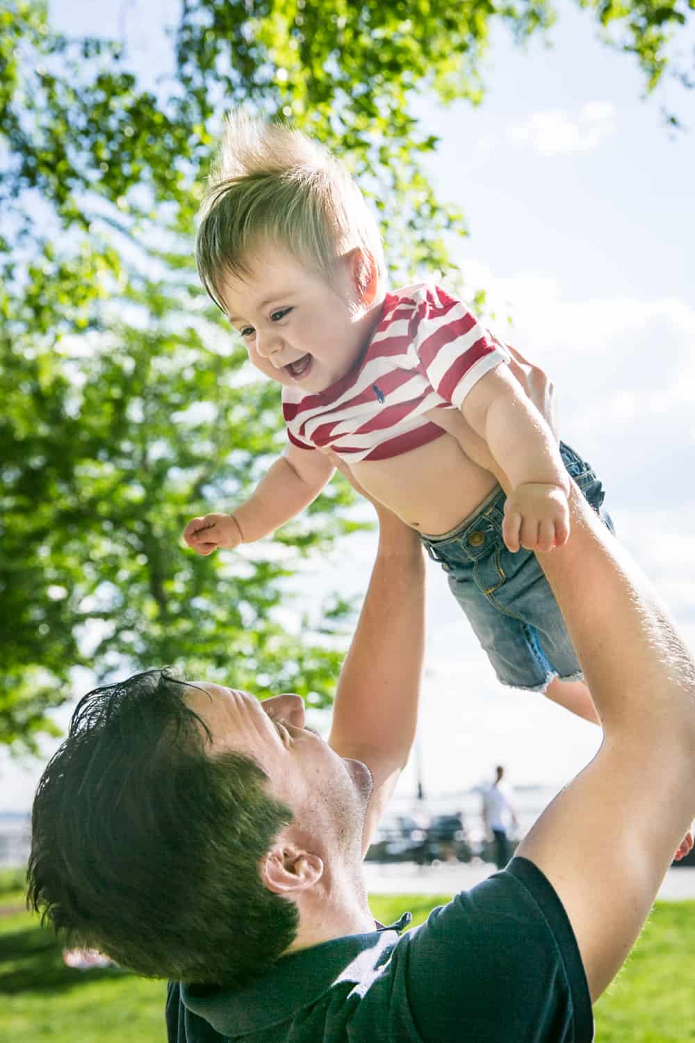 Father lifting baby up in air during a Battery Park family portrait