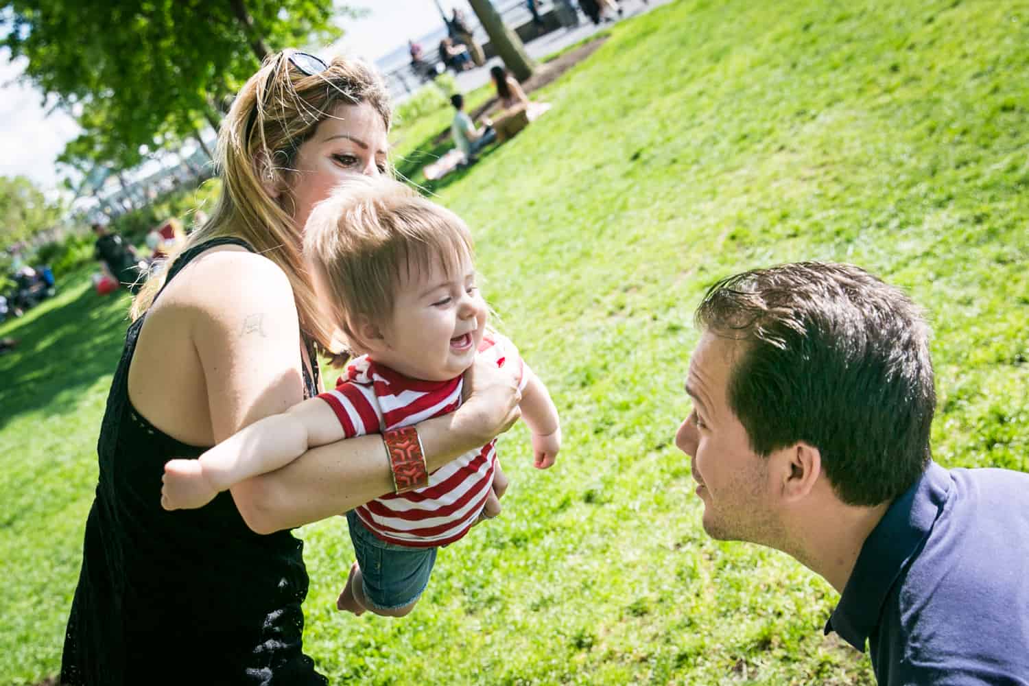 Mother and father playing airplane with baby during a Battery Park family portrait
