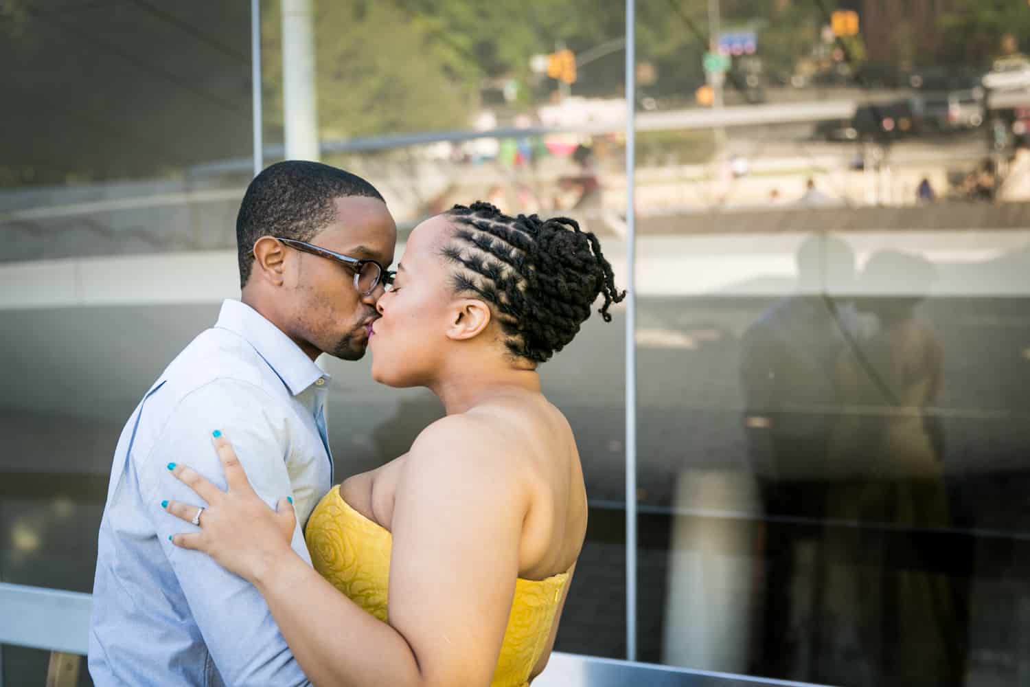 Couple kissing in front of glass wall with reflection