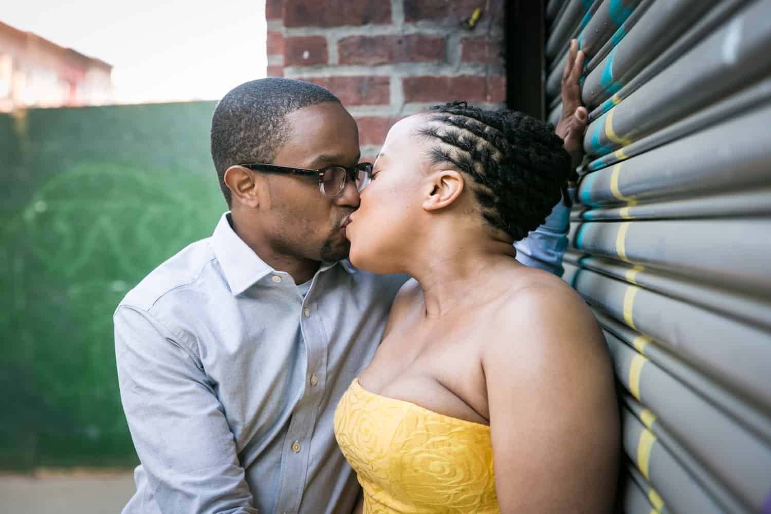 Couple kissing against metal gate in Brooklyn