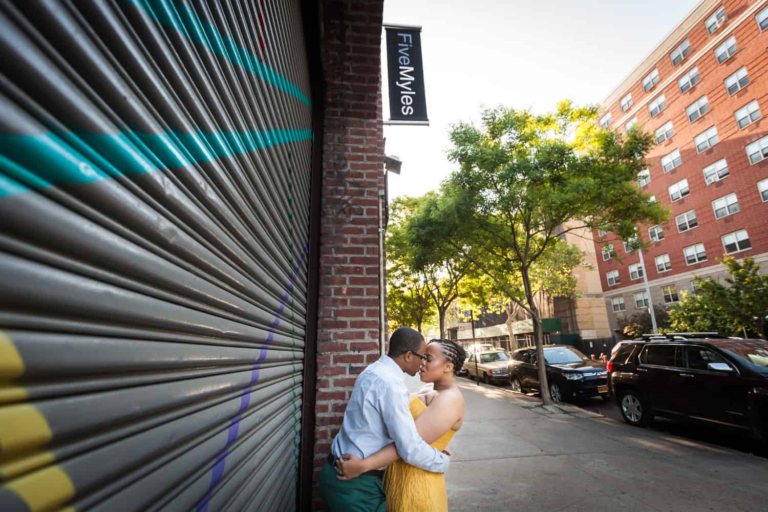Couple kissing in front of metal gate in Brooklyn