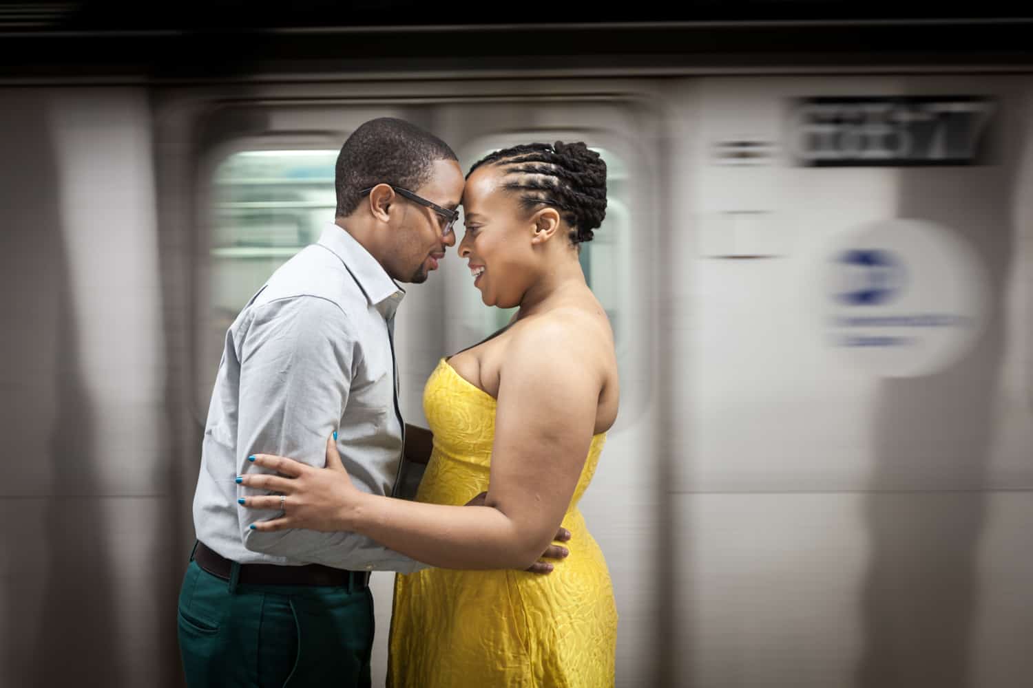 African American couple touching foreheads in front of speeding subway train