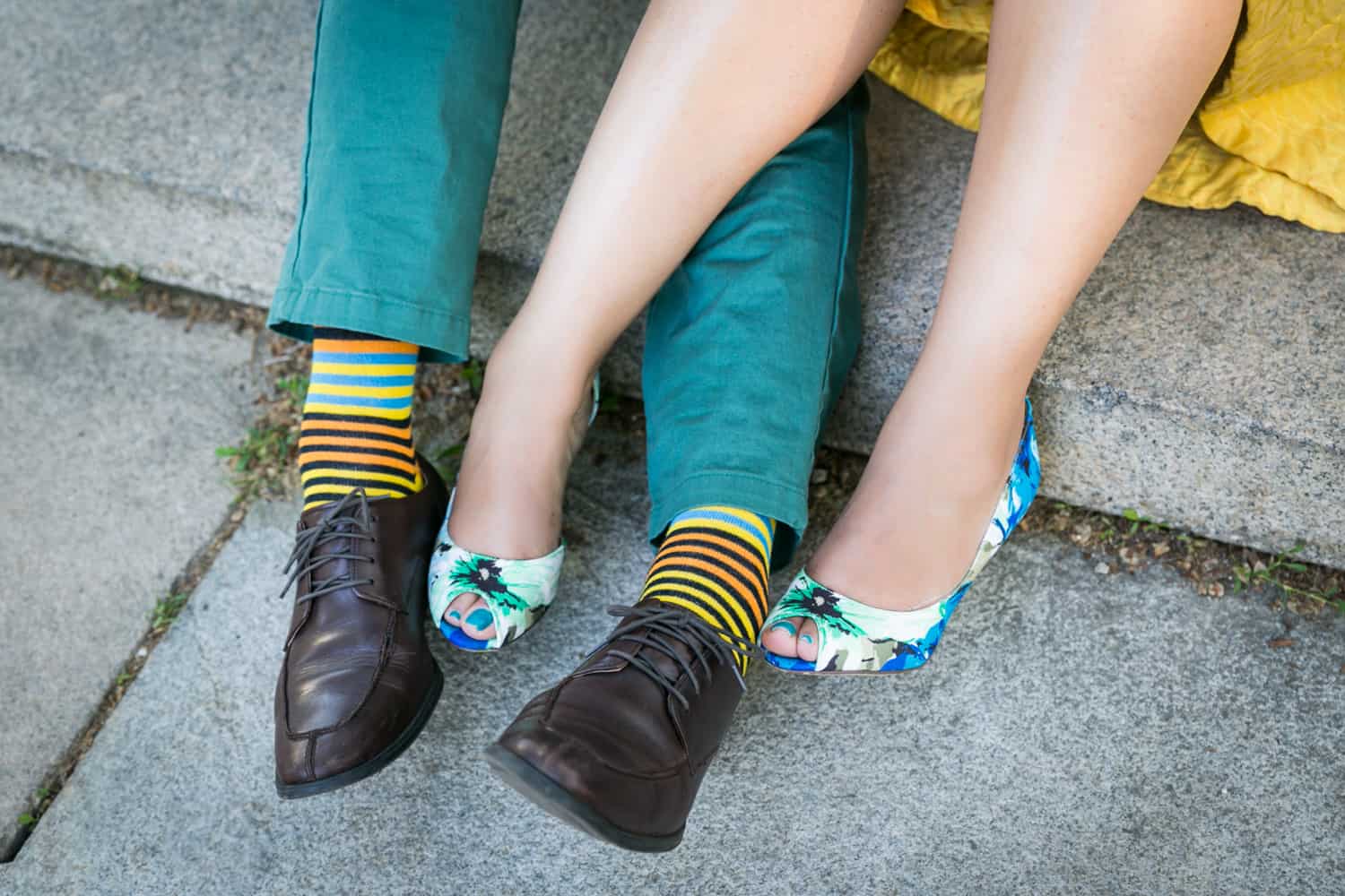Close up on woman wearing colorful floral heels and man wearing colorful socks and black shoes
