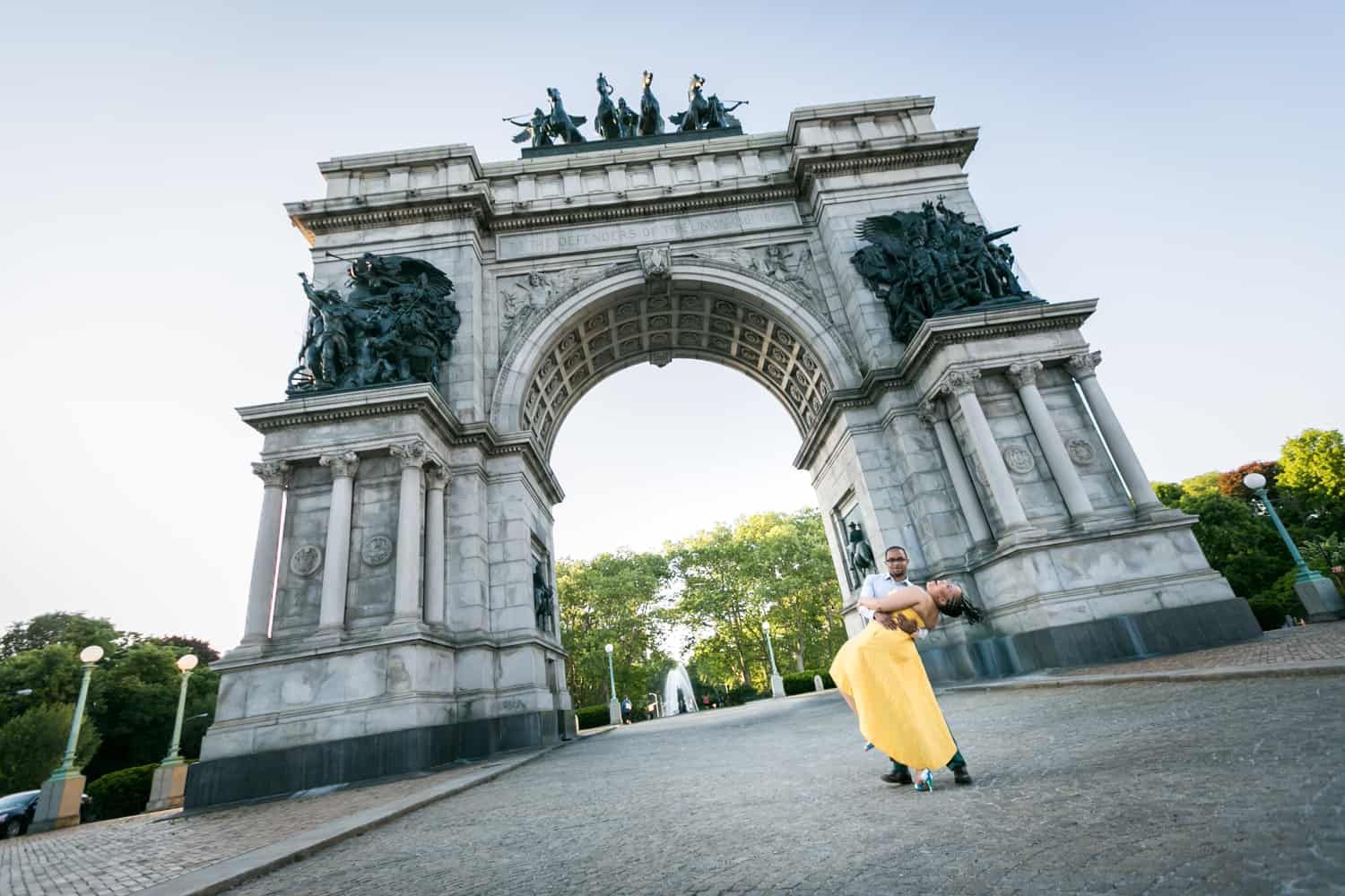 Wide shot of African American couple dancing in front of Grand Army Plaza arch