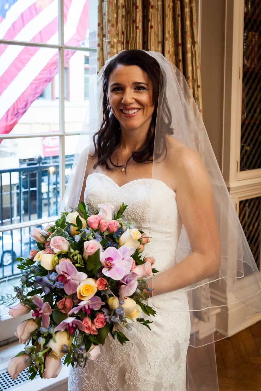 Bride holding bouquet by window for an article on the mysteries of photo editing