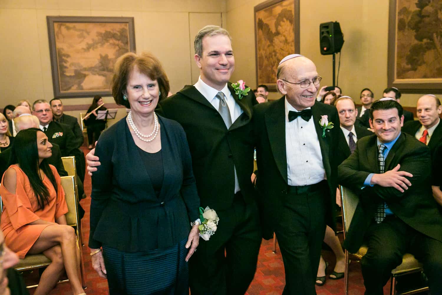 Groom walking with parents down aisle during a Harvard Club wedding ceremony