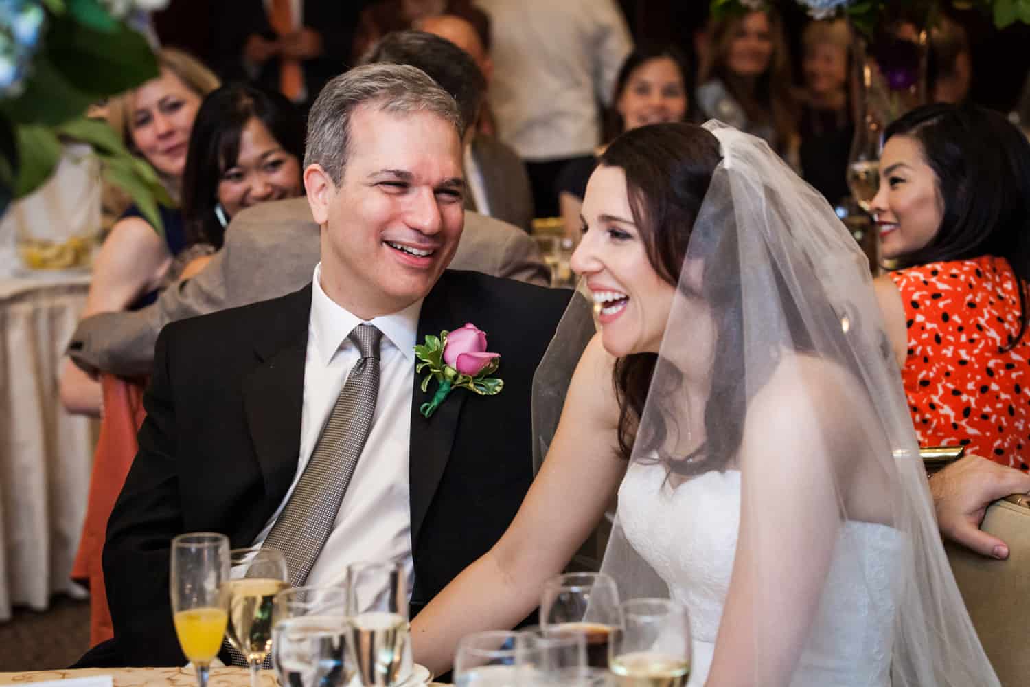 Bride and groom at table smiling at Harvard Club wedding