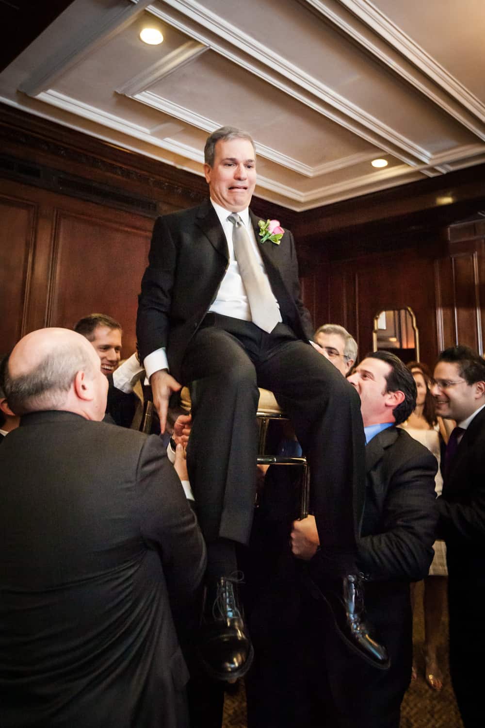 Groom lifted up on chair during hora dance at Harvard Club wedding