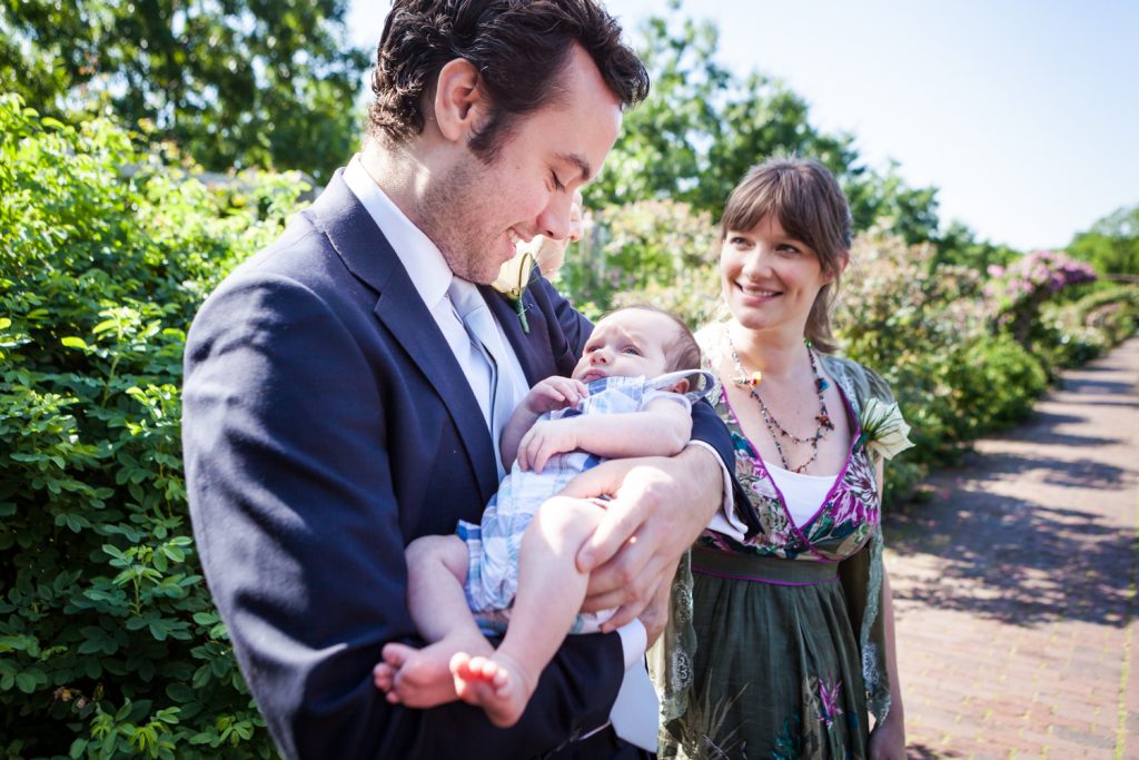 Woman watching man holding baby at an Brooklyn Botanic Garden wedding