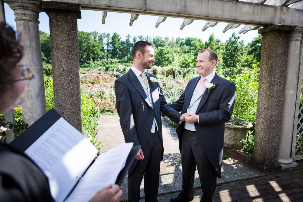 Two grooms during ceremony at an Brooklyn Botanic Garden wedding