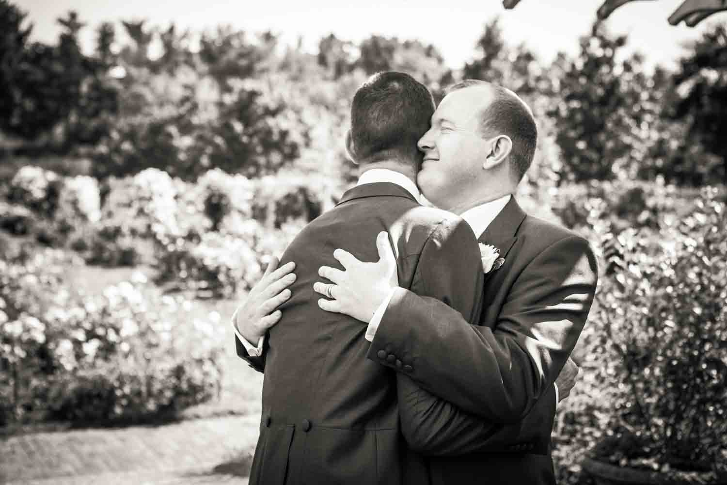 Black and white photo of two grooms hugging