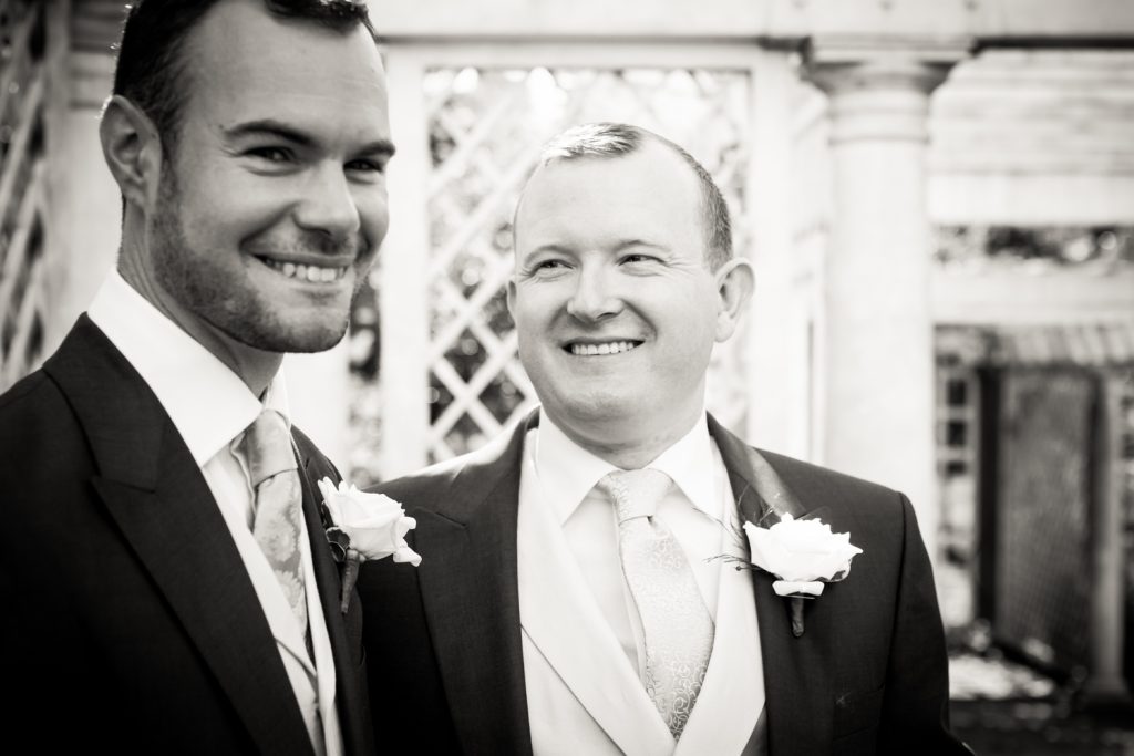 Black and white photo of two grooms in trellis