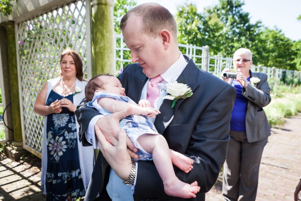 Groom holding baby at an Brooklyn Botanic Garden wedding