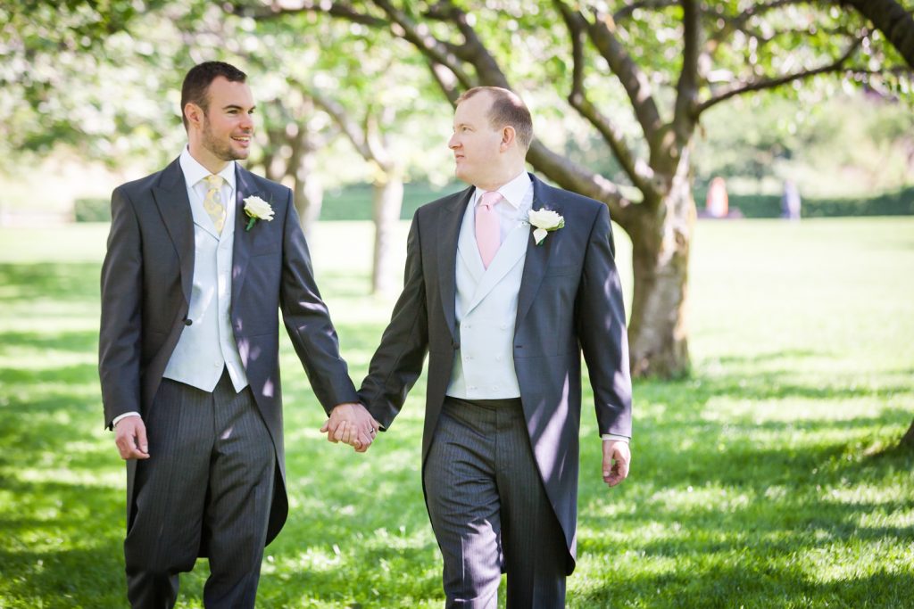 Two grooms holding hands and walking through Brooklyn Botanic Garden