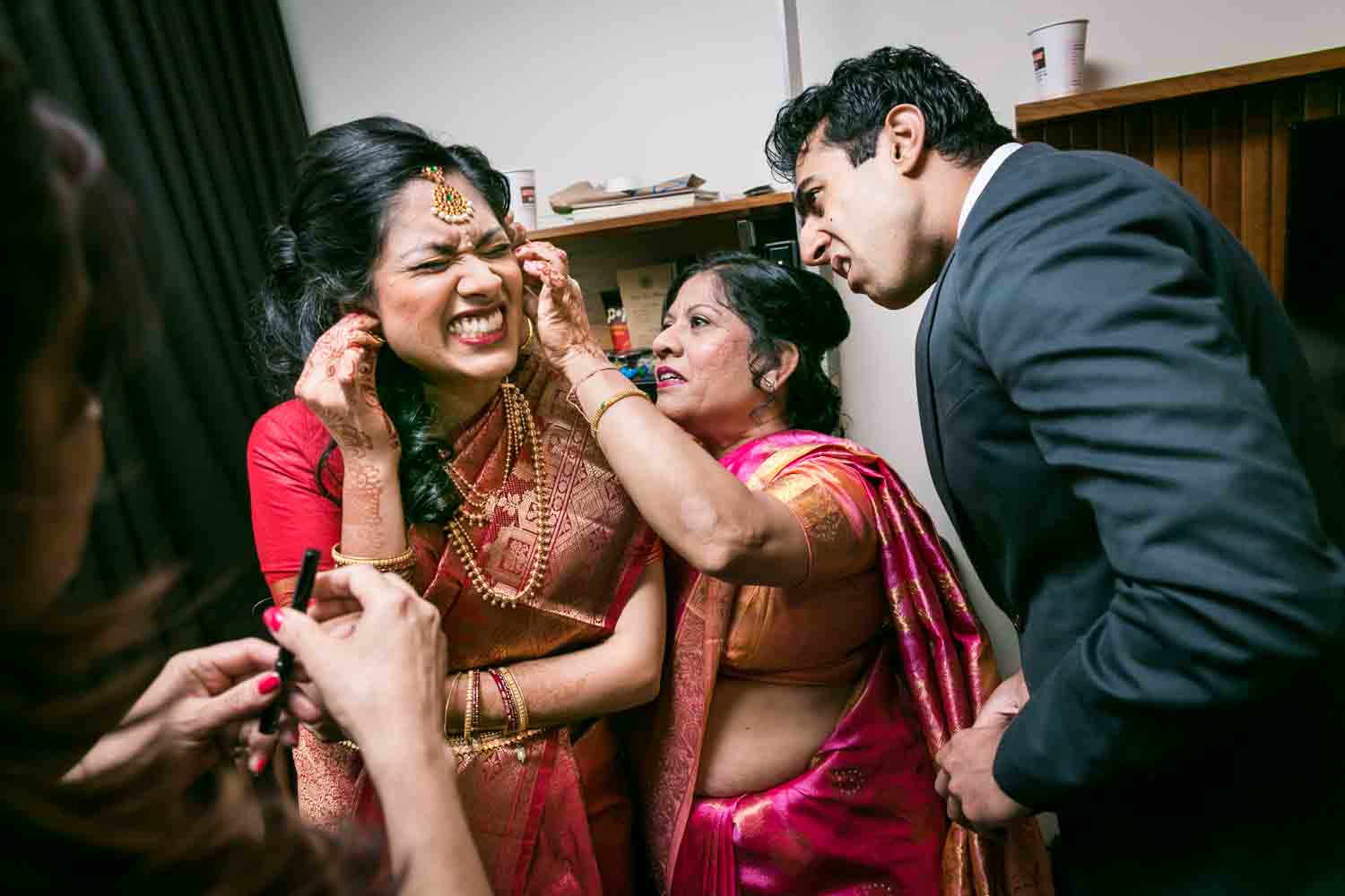 Mother and brother helping Indian bride put in her earrings