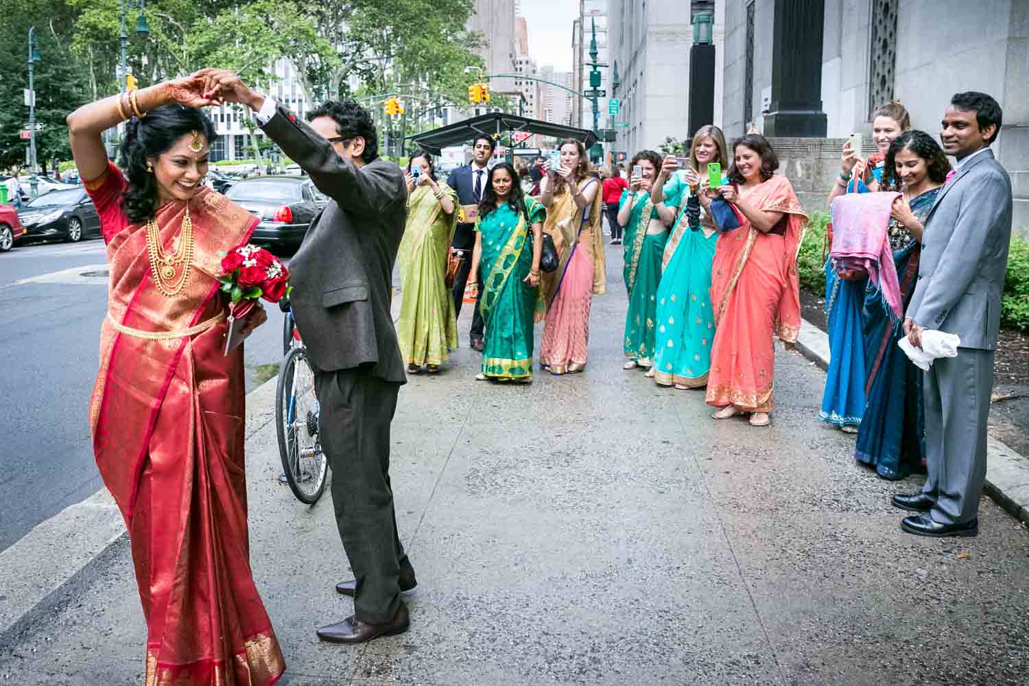Bride and groom dancing in front of bridal party wearing traditional saris