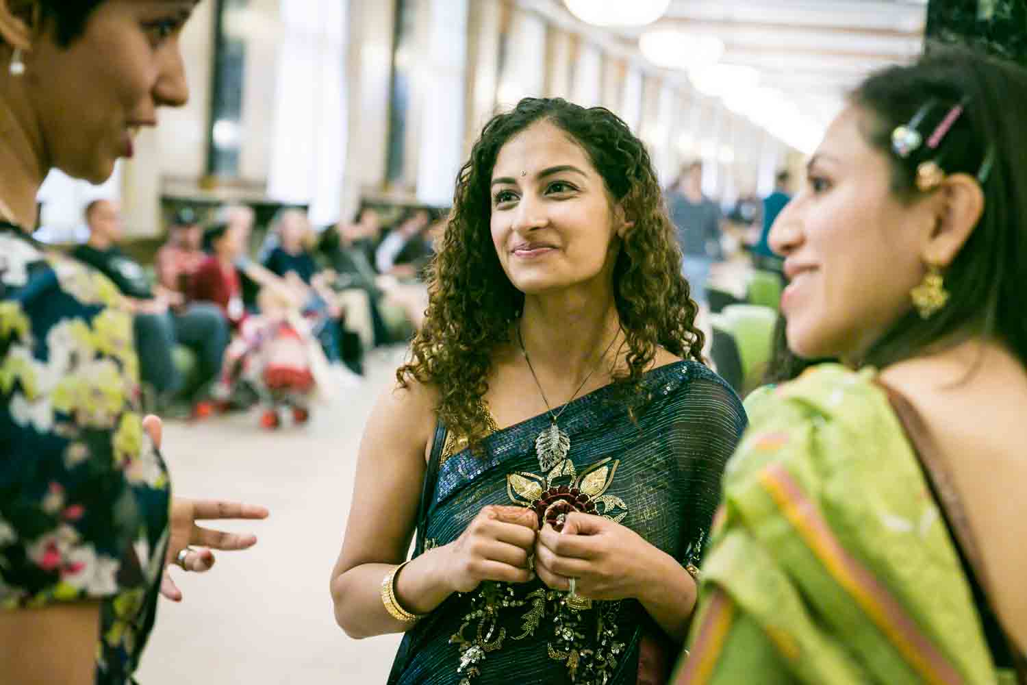 Three women wearing saris and talking at a NYC City Hall Indian wedding