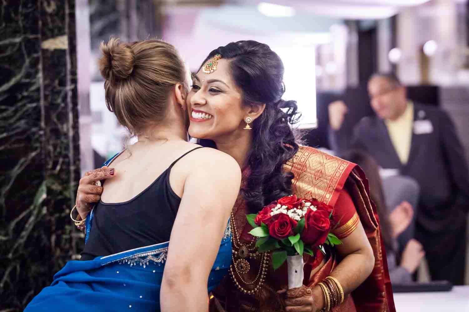 Indian bride hugging woman wearing sari at a NYC City Hall Indian wedding