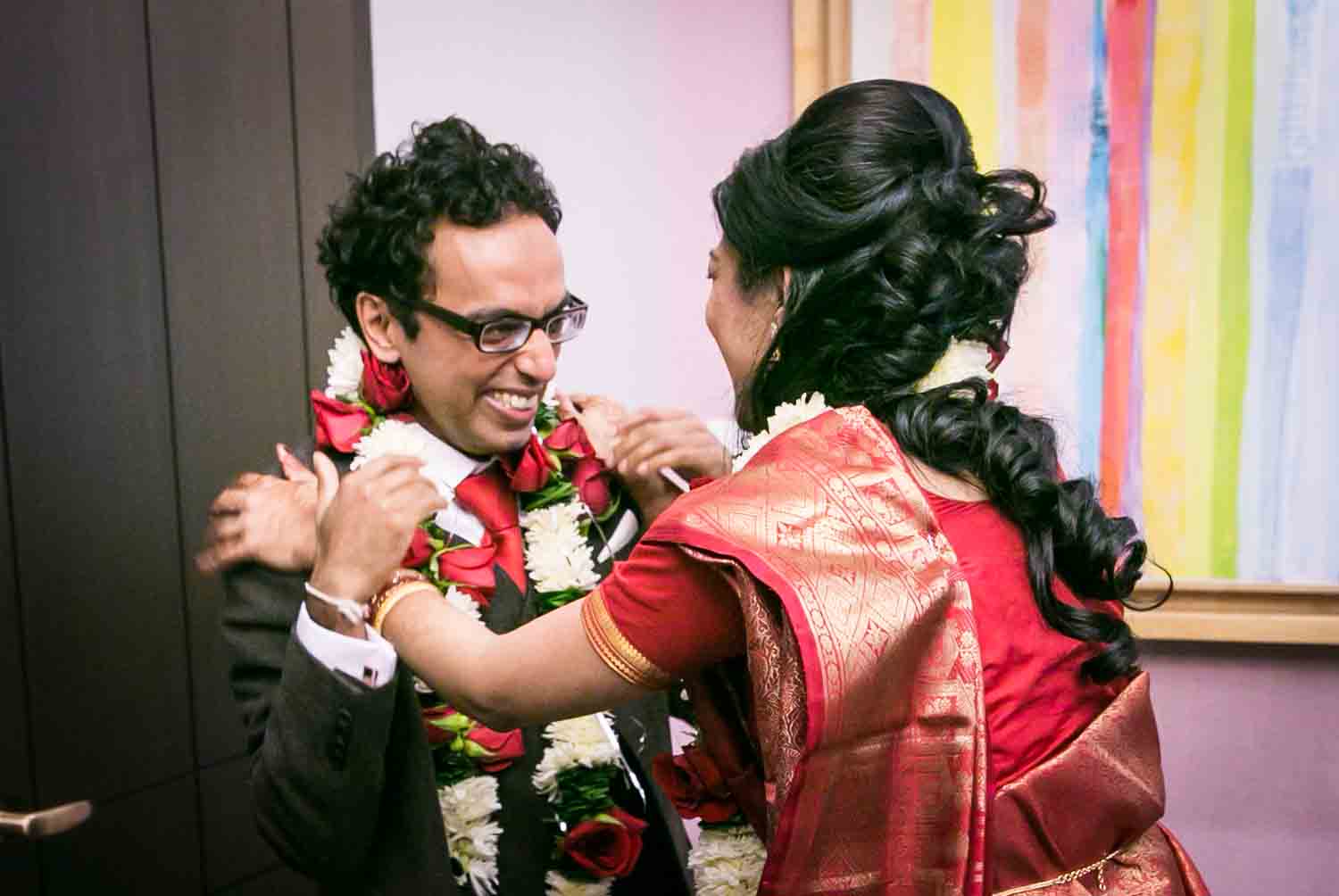 Bride capturing groom with flower garland at a NYC City Hall Indian wedding