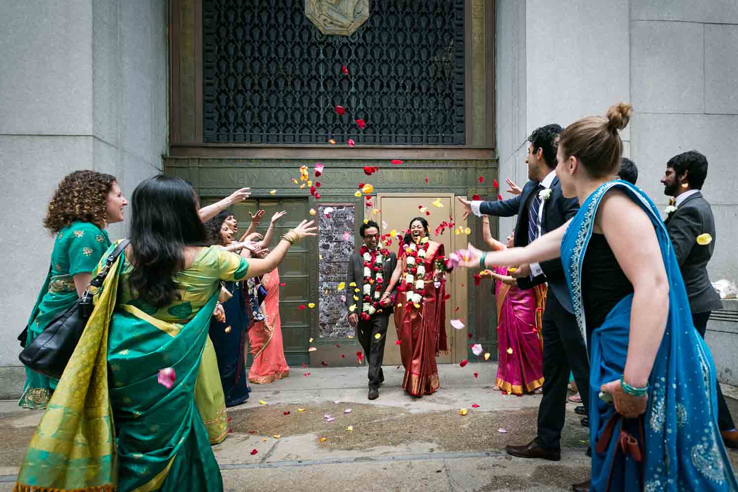 Bridal party wearing saris throwing rose petals at Indian bride and groom at a NYC City Hall Indian wedding