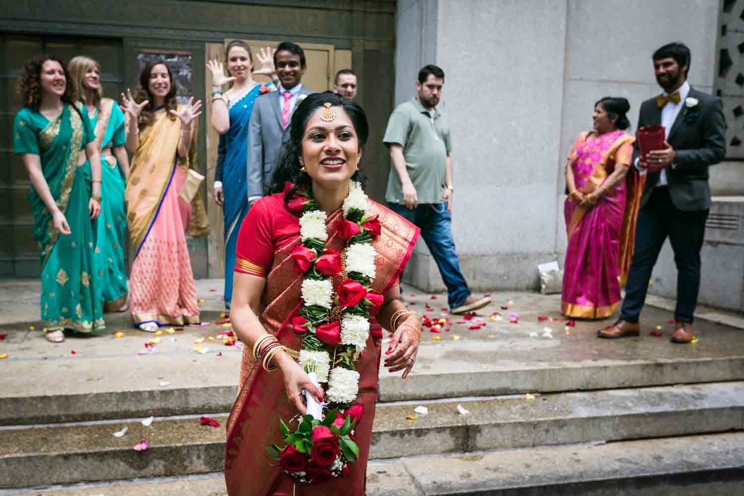 Indian bride in red sari about to throw bouquet at a NYC City Hall Indian wedding