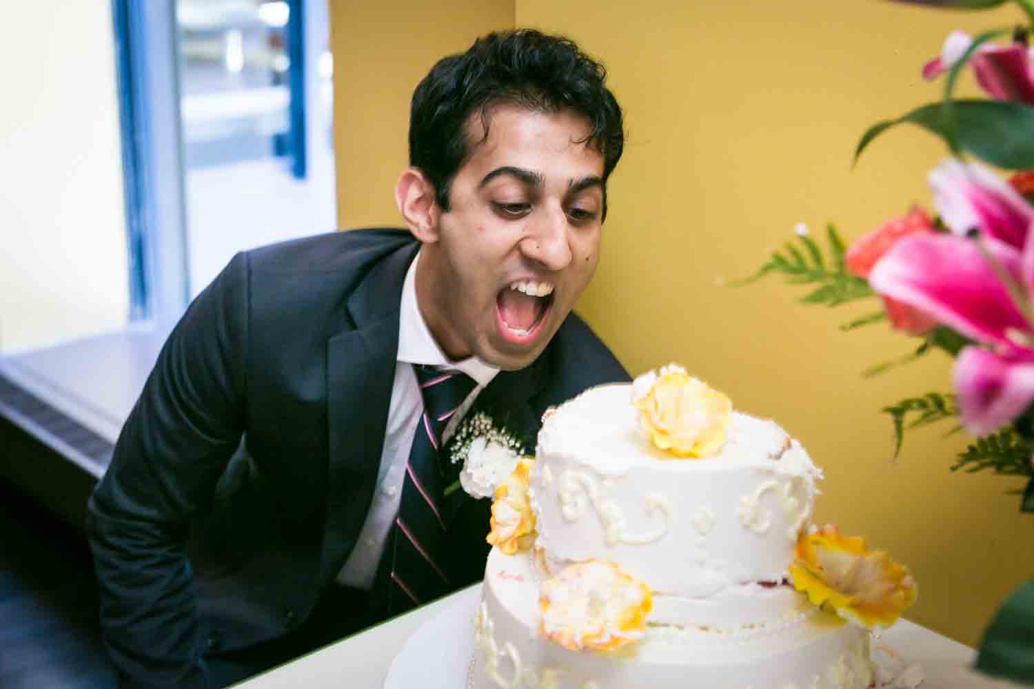 Man about to bite into wedding cake at a NYC City Hall Indian wedding