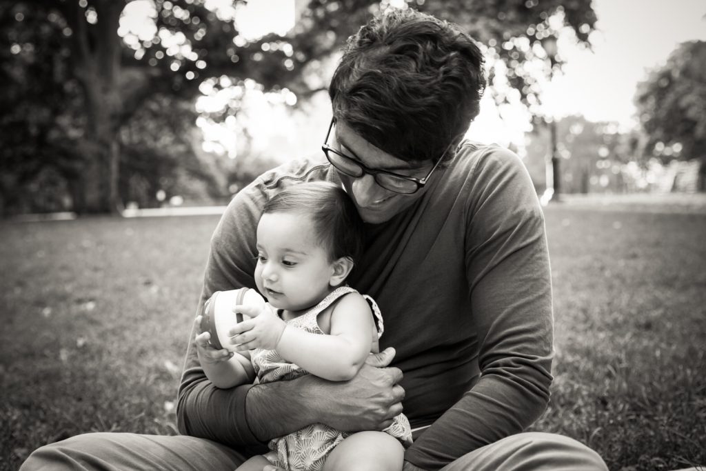 Black and white photo of father playing with toddler in grass