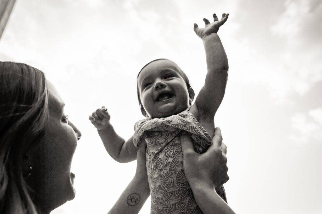 Black and white photo of mother lifting up baby