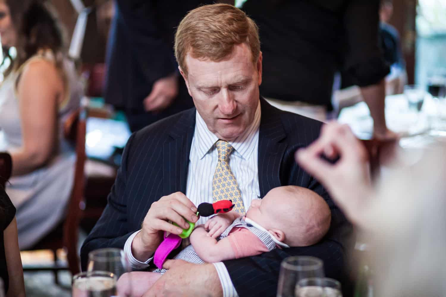 Father of the bride holding a baby at a Hoboken rehearsal dinner