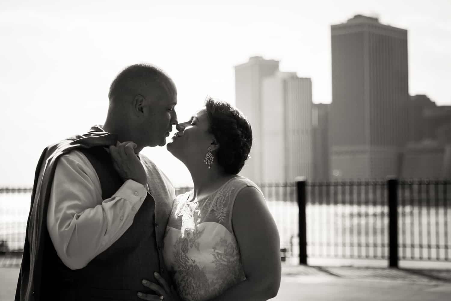 Black and white photo of bride and groom kissing on Brooklyn Promenade