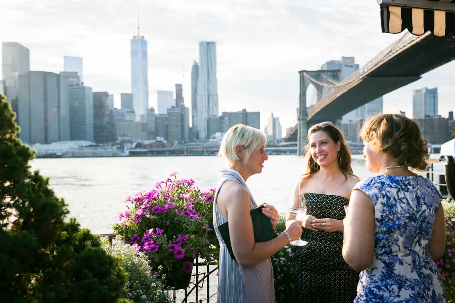 Three female guests chatting outside at a River Café wedding in Brooklyn